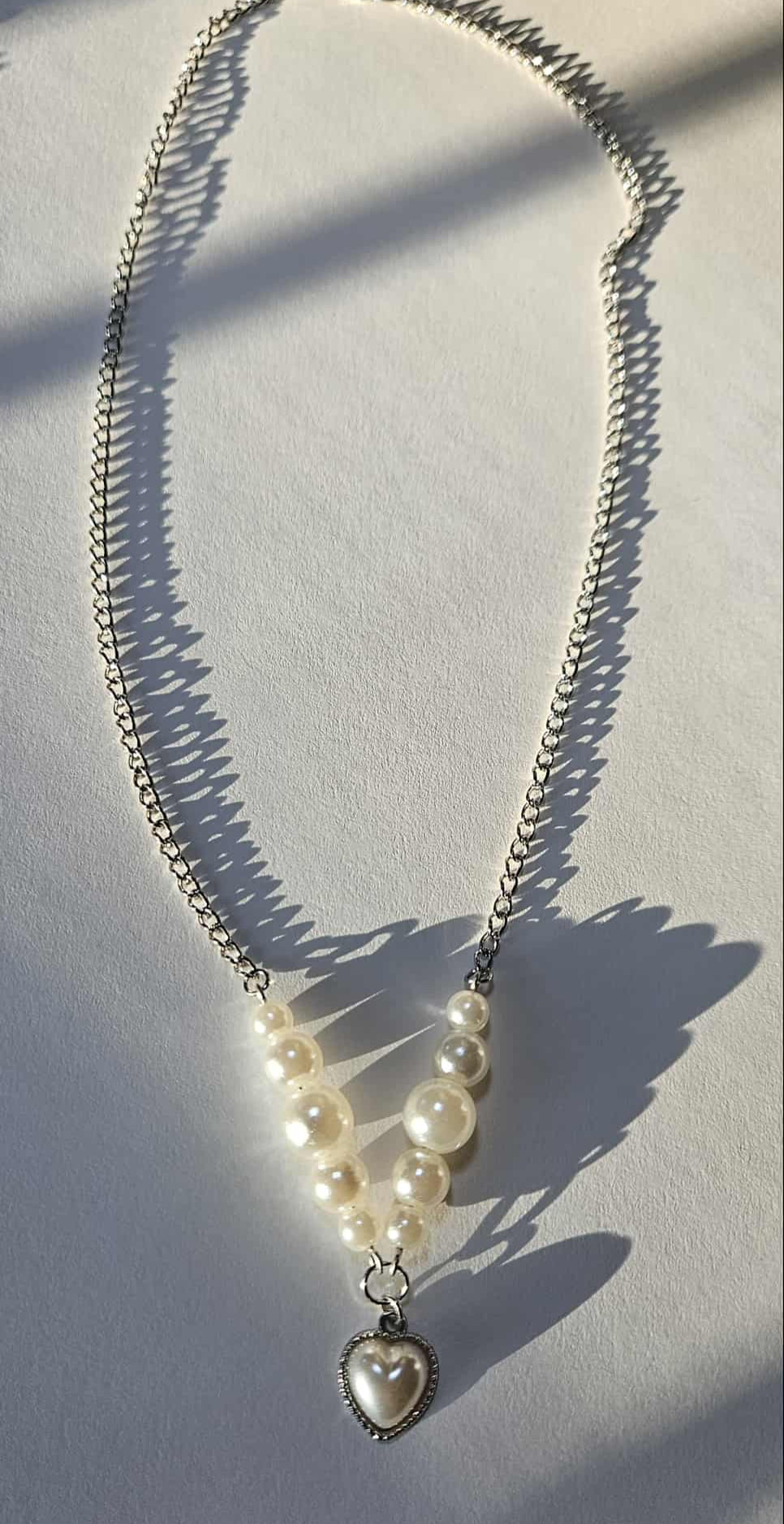 Silver-plated necklace with heart-shaped pearl pendant and pearl beads.